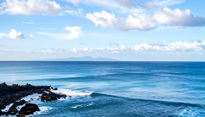 A scenic coastal view with calm, turquoise ocean waves crashing against rocky shores under a bright blue sky with fluffy white clouds