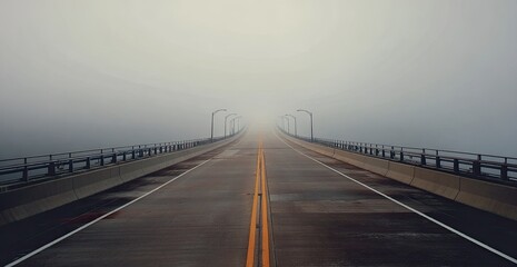 A road stretches through fog, disappearing into the distance under overcast skies, with streetlights