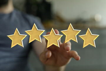 A person's hand reaching for five golden stars, perfect customer experience, high rating and...
