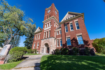 Fototapeta premium Dickinson County Courthouse in Iron Mountain, Michigan, historic red brick building with clock tower under clear blue sky