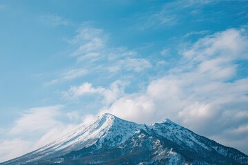 Snow-capped mountain peaks under a clear blue sky with fluffy white clouds