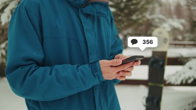 Snowboarder man rider in the snow at ski resort, using his smart phone while resting in the mountains, sport application, navigation and booking, communication, sport lifestyle