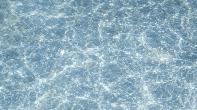 Stunningly clear blue water rippling under bright sunlight, casting shimmering caustic patterns on the sandy sea floor  tranquil, summer coastal background for peaceful projects