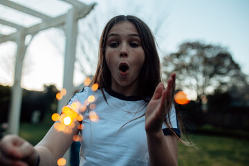 Young preteen girl holding a sparkler in the garden