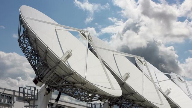 Multiple Satellite Dishes Against a Dynamic Sky