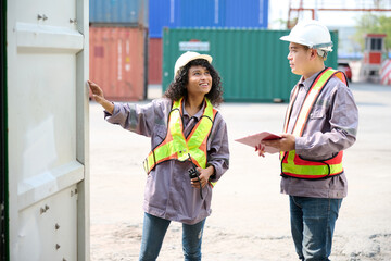 Workers collaborate in an outdoor cargo yard, discussing plans in front of shipping containers