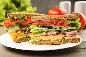 Tasty sandwiches with ham, cheese and vegetables on wooden table, closeup