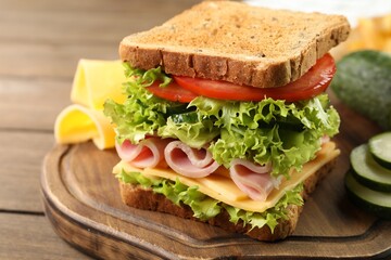 Tasty sandwich with ham, cheese and vegetables on wooden table, closeup