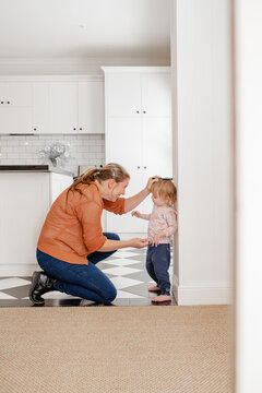 Mother measuring toddler daughters height against the wall