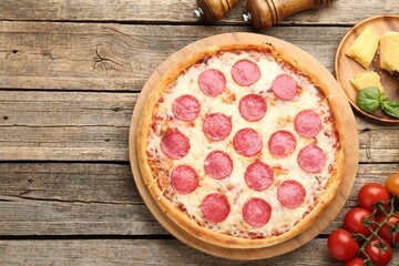 Delicious pepperoni pizza and ingredients on wooden table, flat lay. Space for text