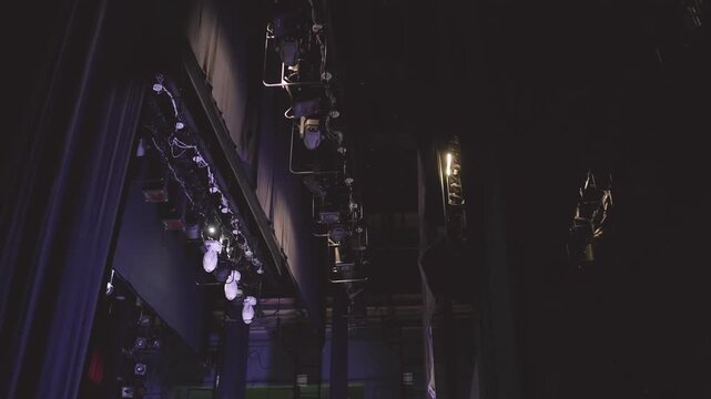 Backstage theater scene with spotlights, rigging and curtains glowing in dramatic light, preparing an empty stage for performance