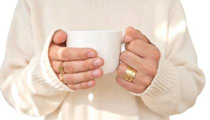 Close-up of hands holding a white mug, wearing rings, cozy sweater aesthetic