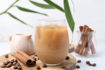 Tasty iced coffee in glass and beans on white tiled table, closeup