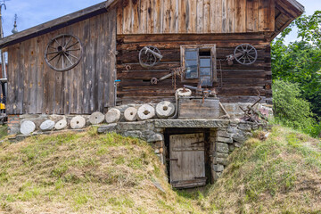 Old wooden house featuring rustic tools and millstones in Sekowa, Poland