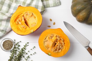 Whole and cut pumpkins with spices on white wooden table, flat lay