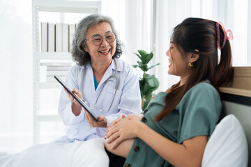 A pregnant woman sits on a hospital bed during a prenatal consultation with a smiling doctor. The scene highlights maternal health, professional care, and supportive communication in a clinical.