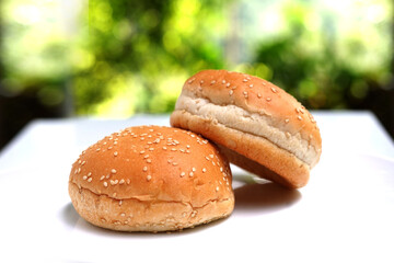 Freshly baked burger buns bread roll on white table.