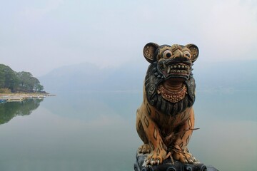 Lion guardian statue at Pura Ulun Danu Batur, Bali, Indonesia, captured in misty morning by the lake. Majestic and cultural, ideal for travel, heritage, faith, and tourism themes. © Arlina Elsiska