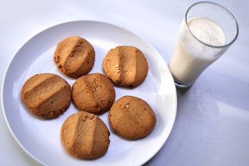 Golden Crunchy Cookies Arranged on White Dish with milk glass on white.