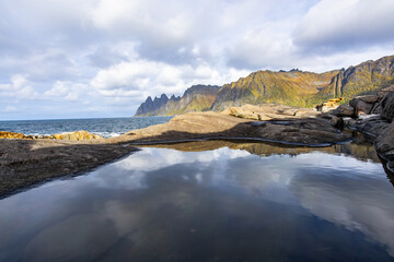 Autumn landscape of Senja Island in Northern Norway with colorful foliage, mountains, and a serene fjord.