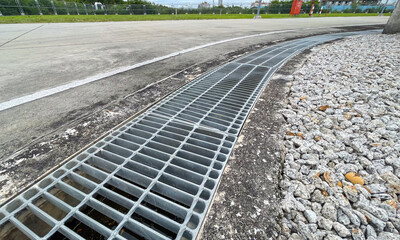 Concrete road drainage channel with a steel grate cover designed to create an even surface and...