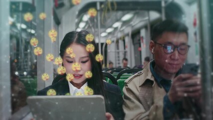 Asian woman using tablet and chatting online while sitting on train. Man beside her holding smartphone and listening to music with earbuds. Floating emoji icons glowing around people. Public transport - Powered by Adobe