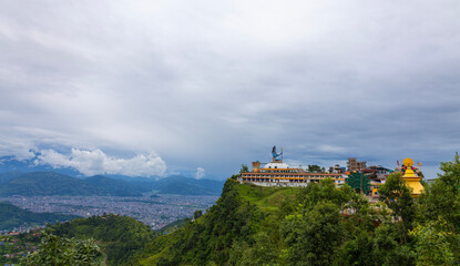 Magnificent view of the Pumdikot Shiva Statue overlooking Pokhara Valley, Nepal, surrounded by lush green hills and dramatic sky ,ideal for travel blogs, tourism posters and cultural projects.
