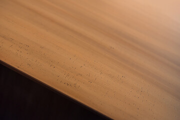 Close-up view of brass surface. Edge of brass top rectangular table. Textured warm-colored metal with lines and dots. 