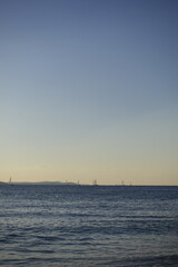 Sailboats sailing on the sea under a clear blue sky at sunset