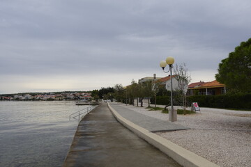 Coastal promenade with a view of the sea and a town under a cloudy sky