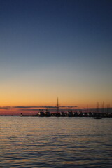 serene sunset over a marina with boats and calm water reflecting the sky's colors