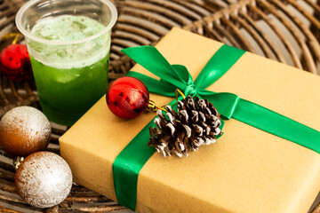 gifts with green ribbons, green cold drinks and some Christmas tree decorations. All placed on a rattan table.