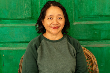 portrait of a woman sitting on a bench with green door as background