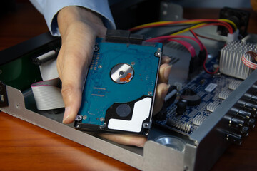 A technician is installing a hard drive into a CCTV camera recorder.