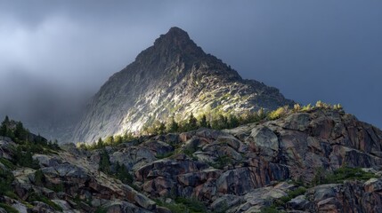 Dramatic mountain peak surrounded by clouds and lush greenery captured in natural light