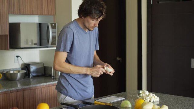 A young man is cooking food in the kitchen, focusing on preparing a delicious homemade meal. A relatable and warm moment of homemaking, creativity, and culinary enjoyment in a cozy setting.
