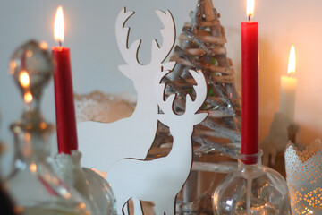 Table set for Christmas meal, with plates, wine, decorations and lit candles. Selective focus.