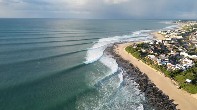 Drone shot from above of ocean waves with surfers surfing at Supertubes in Jeffreys Bay or J-Bay in South Africa.