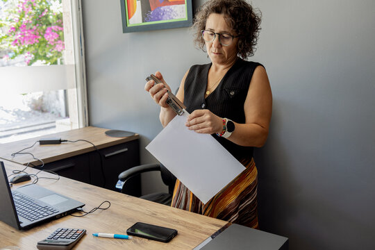 Woman using a stapler while standing in office