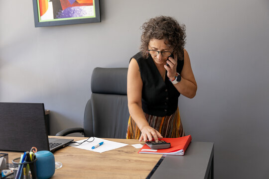Businesswoman multitasking with phone and calculator