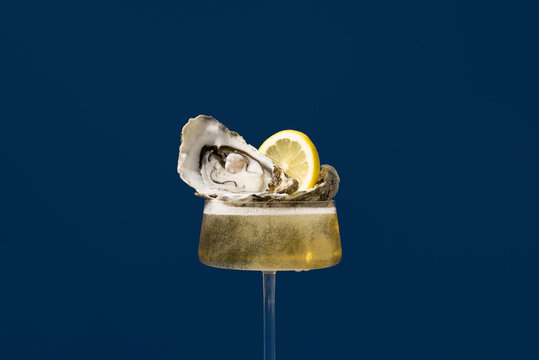 Champagne glass with oyster and lemon on blue