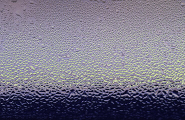 Macro image of water condensation and dripping streaks on a window pane. Household energy loss, poor insulation, and environmental impact.