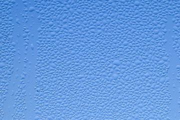 Macro image of water condensation and dripping streaks on a window pane. Household energy loss, poor insulation, and environmental impact.