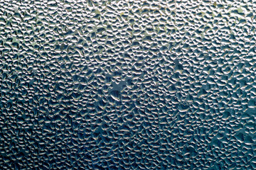 Macro image of water condensation and dripping streaks on a window pane. Household energy loss, poor insulation, and environmental impact.