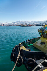 Yellow pilot boat at harbor with snow capped mountains and industrial port view © TashaAsha