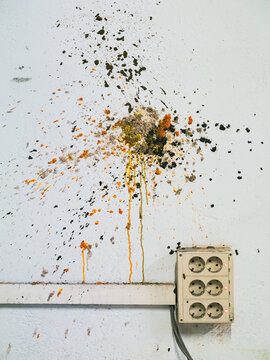 Electrical outlet on a worn wall with colorful stains