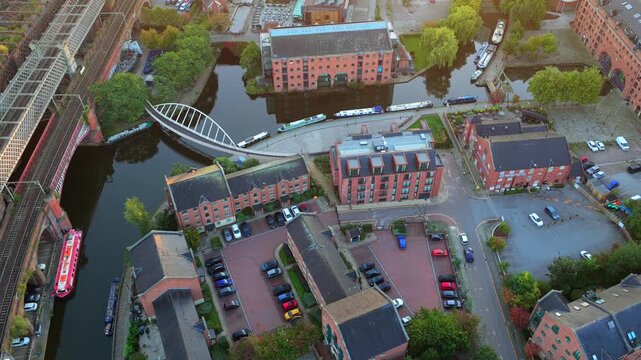 Top-down aerial video of Castlefield Footbridge and Merchants&rsquo; Warehouse along Bridgewater Canal in Manchester UK 