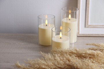 Decorative LED candles, spikes and frame on wooden table indoors, space for text