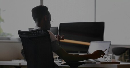 Holding pen and sipping from mug while office worker typing on laptop at desk, copy space