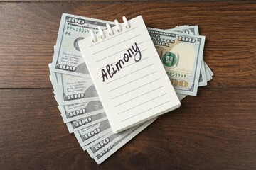 Naklejka premium Notebook with word Alimony and money on wooden table, top view
